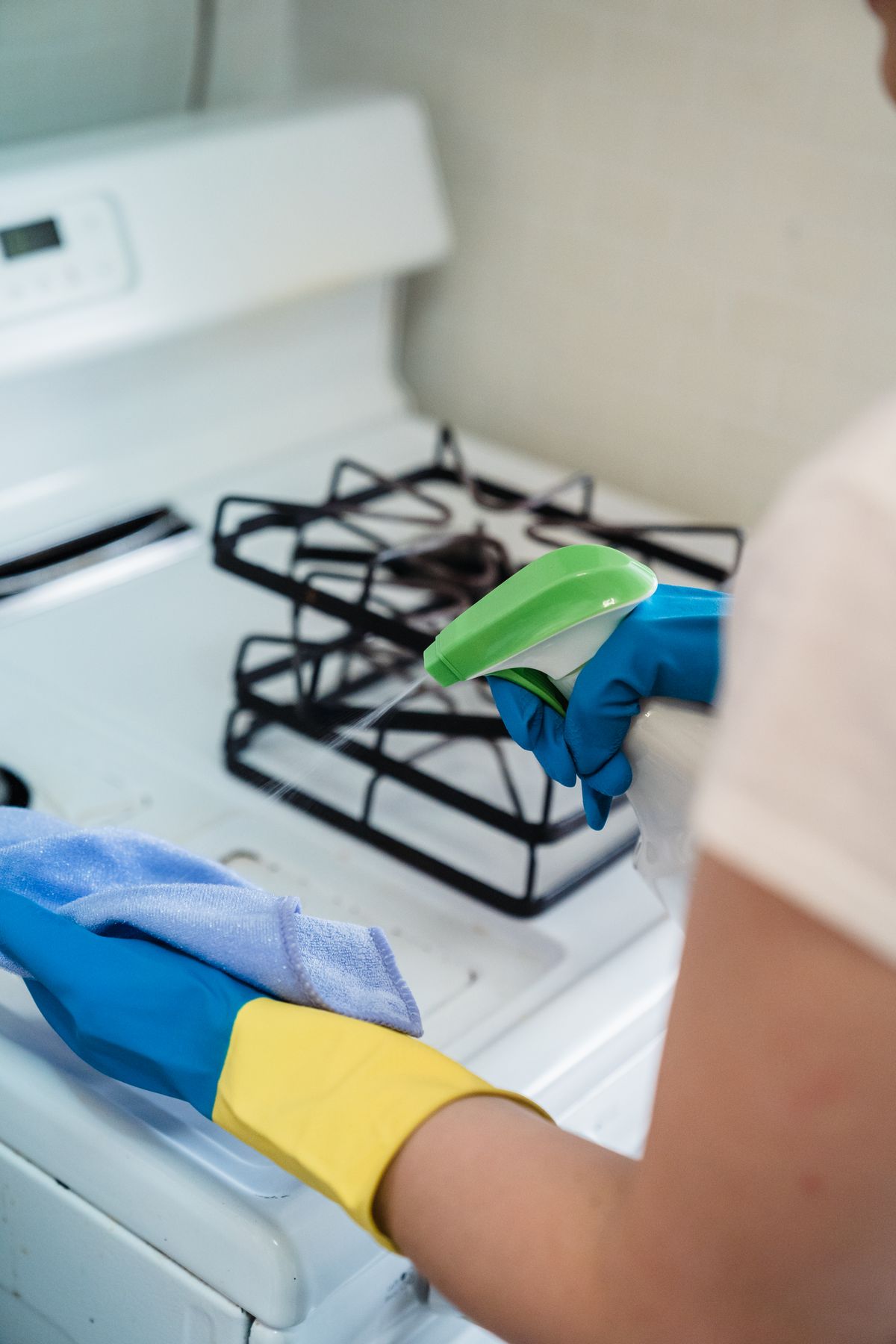 Spraying cleaner onto a cloth to wipe down a kitchen appliance