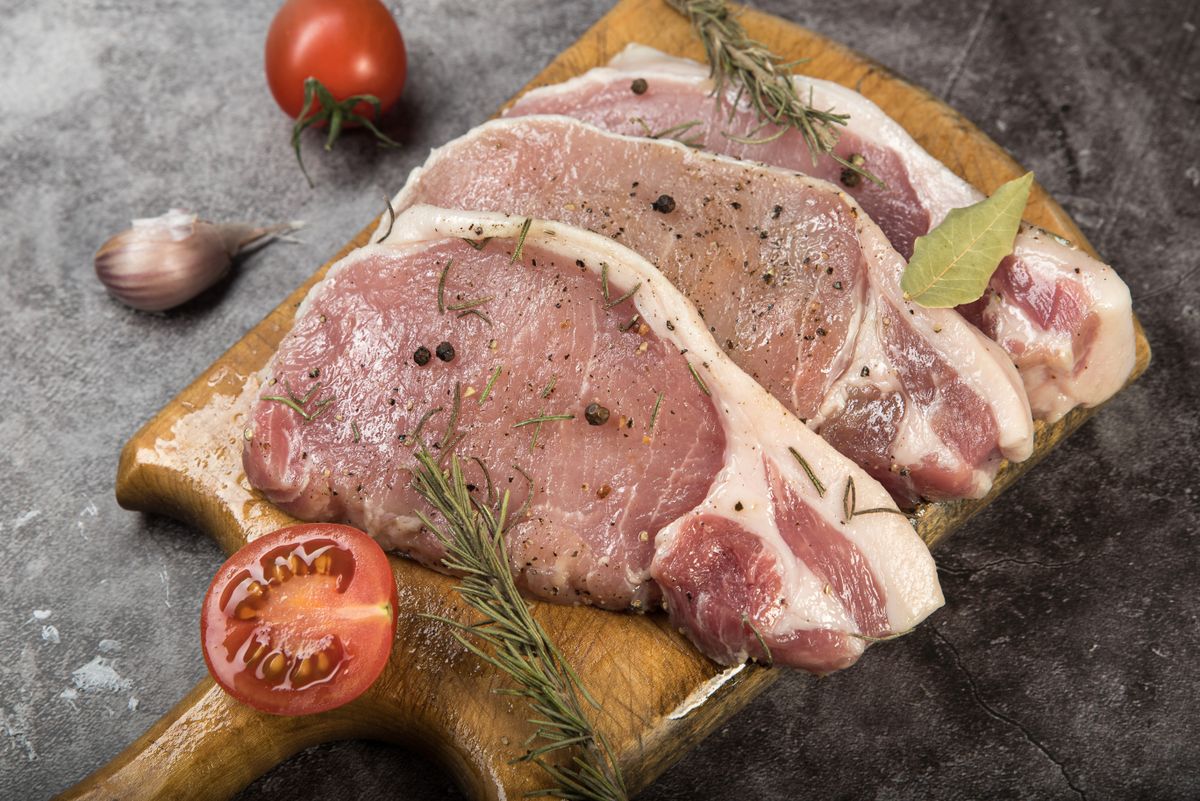 Raw pork chops on a wooden chopping board ready to season